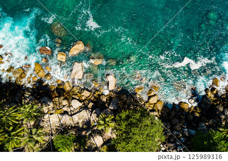Aerial view Top down seashore, Waves crashing on rocks cliff, Beautiful sea surface in sunny day summer background, Amazing seascape top view seacoast at Phuket Thailand 125989316