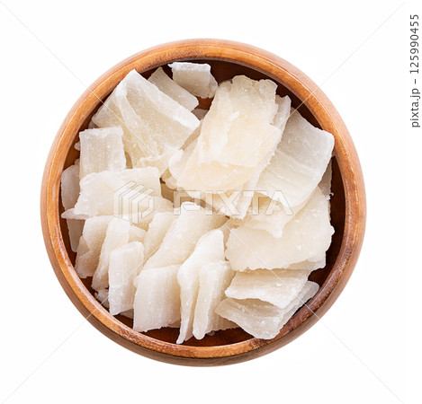 Aloe vera slices, dried and sugared, in wooden bowl. Unique dessert or snack with chewy texture, and with sweet and tangy flavor. Translucent and opaque chips of the leaves of the succulent Aloe vera. 125990455