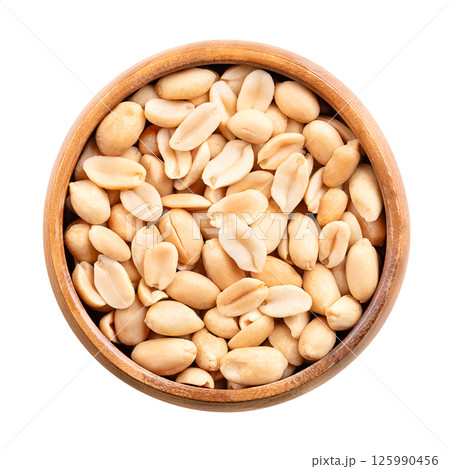 Roasted peanuts in a wooden bowl. Ready-to-eat crunchy snack food, made from the fruits of Arachis hypogaea, also known as groundnut, goober, pindar or monkey nut. Close up, isolated from above. Photo 125990456