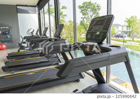 Fitness gym club with row of treadmills for fitness cardio training. Healthy lifestyle concept. Modern gym interior with equipment. Fitness gym club with row of treadmills for fitness cardio training. Healthy lifestyle concept. Modern gym interior with equipment. 125990842