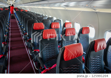 Empty interior of cabin of airplane with rows of black and red seats in daytime before the flight Empty interior of cabin of airplane with rows of black and red seats in daytime before the flight 125991204