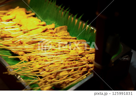 thai satay skewers with grilled pork and dipping sauces served  125991831