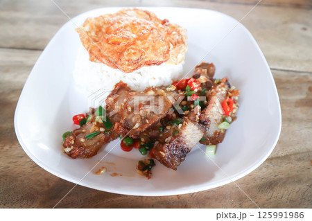stir fried pork or deep fried pork , fried pork or crispy pork and rice with fried egg or sunny side up egg or pork and rice 125991986