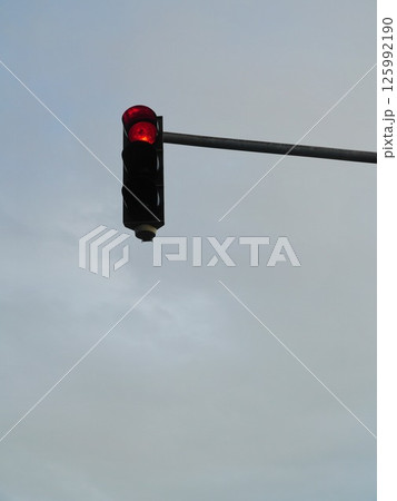A red traffic light is lit up on a cloudy day A red traffic light is lit up on a cloudy day 125992190