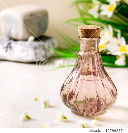 Beautiful pink transparent bottle of perfume with flowers 125992374