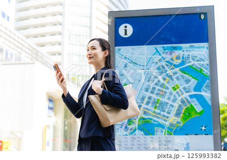 地図とスマホを見て場所を確認する女性ビジネスパーソン 地図とスマホを見て場所を確認する女性ビジネスパーソン 125993382