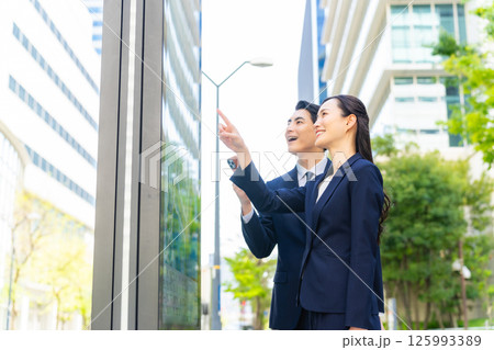 地図とスマホを見て場所を確認する男女ビジネスパーソン 地図とスマホを見て場所を確認する男女ビジネスパーソン 125993389