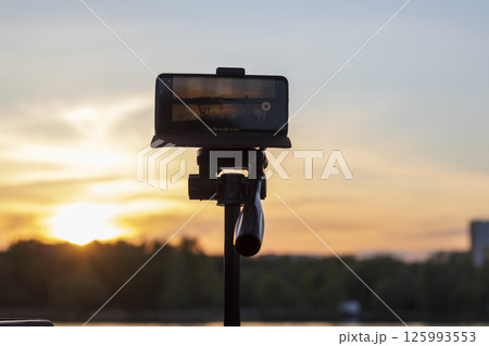 Cell phone on the tripod capturing sun set moment Cell phone on the tripod capturing sun set moment 125993553
