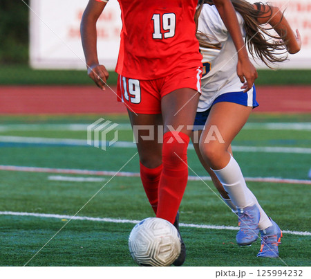 Female Soccer Player Running with the Ball being Chased by Competitor 125994232