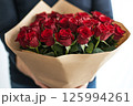 Bouquet of fresh red roses wrapped in kraft paper in the man hands on white background, empty space for text. Template of Valentines Day banner, card, flower delivery, shop advertisements 125994261