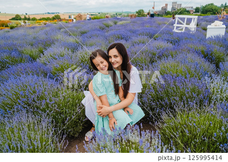A beautiful European girl with a young woman in a field of purple flowers. A beautiful European girl with a young woman in a field of purple flowers. 125995414