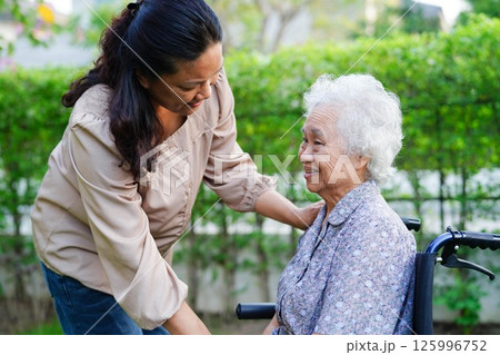 Caregiver help Asian elderly woman disability patient sitting on wheelchair in park, medical. 125996752