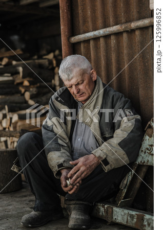 A pensioner sits quietly, his face full of sadness.  125996852