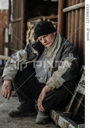 A pensioner sits quietly, his face full of sadness.  125996853