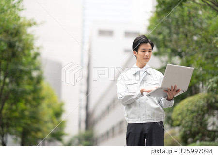 作業服を着てパソコンを持つ男性 125997098