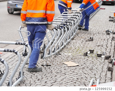 Three men in orange and blue jackets are working on a row of metal racks Three men in orange and blue jackets are working on a row of metal racks 125999152