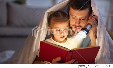 Parent Reading to Child Under Blanket Fort with Flashlight 125999293