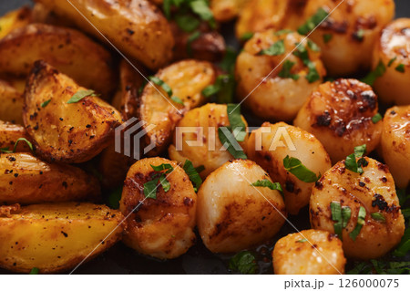 roasted scallops with baked potatoes wedges on a black plate 126000075