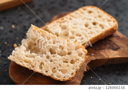 ciabatta bread sliced in half for sandwich on olive board 126000138
