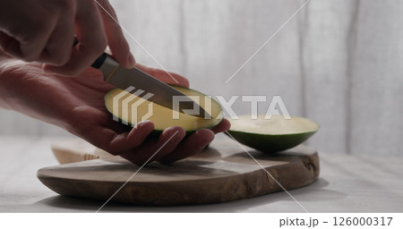 man cut green mango on olive wood board 126000317