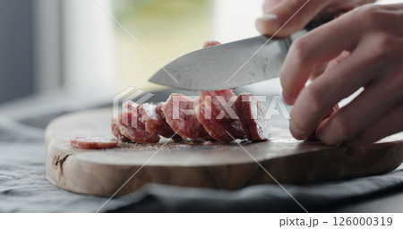 man slicing salami on olive board man slicing salami on olive board 126000319
