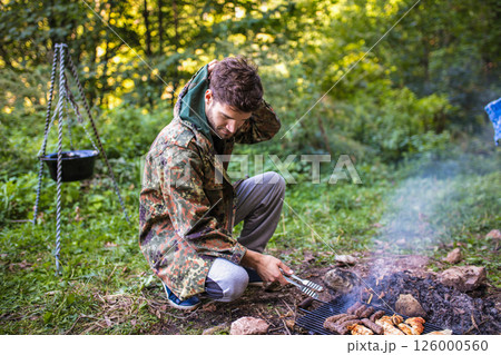 Hunter grilling meat in the woods after hunting trip 126000560