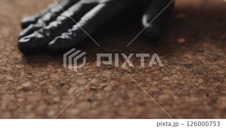 man hands in black gloves touch dark cork surface 126000753