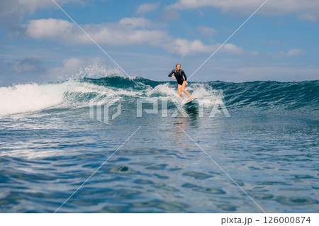Woman surfer on a perfect blue wave on a sunny day 126000874