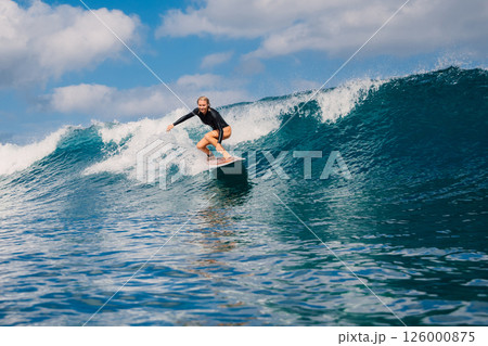 Smiling female surfer riding on ocean wave Smiling female surfer riding on ocean wave 126000875
