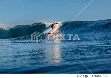 Woman surfer rides on perfect blue wave, surfing in ocean. 126000878