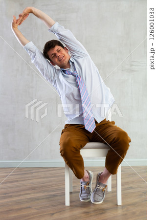 Young guy office worker doing exercises on chair 126001038