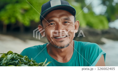 A smiling man holding a bunch of seaweed, capturing the joy of coastal life and sustainable harvesting 126002405