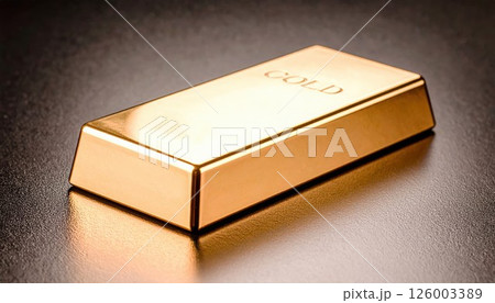 Close-up of a shiny gold bar with engraved markings resting on a smooth surface, highlighting precious metal investment and wealth symbol in a minimal setting 126003389