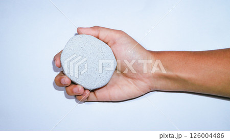 Girl holding a pumice stone on white background Girl holding a pumice stone on white background 126004486