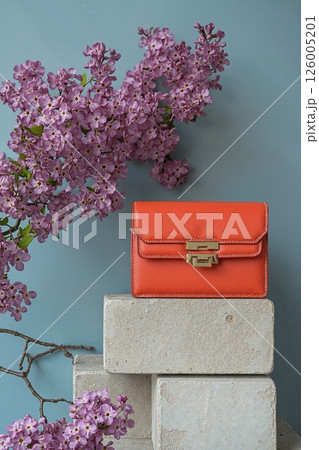 Elegant spring design with orange bag and purple blossoms for fashion and floral concept 126005201