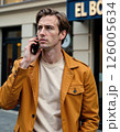 Urban elegance: stylish man in mustard jacket taking a phone call 126005634