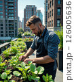 Urban gardening serenity: young man tending to lush green plants on a rooftop garden in the city 126005636