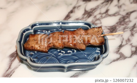 close up of a Japanese grilled ox tongue skewer in five pieces on a blue plate on a marbled table taken in an izakaya restaurant 126007232