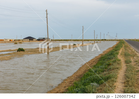 Flooded power line alongside asphalt road after disaster in Kazakhstan Flooded power line alongside asphalt road after disaster in Kazakhstan 126007342