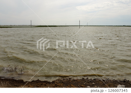 Flooded steppe landscape with power line poles submerged in water after flood in Kazakhstan Flooded steppe landscape with power line poles submerged in water after flood in Kazakhstan 126007345