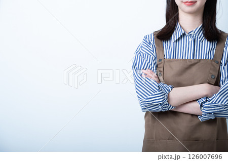 腕を組んで立つエプロン姿の女性 126007696