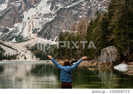 Mountain lake Braies in Italy. Girl in front of the lake looks at the beautiful landscape Mountain lake Braies in Italy. Girl in front of the lake looks at the beautiful landscape 126008723
