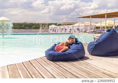 Child Relaxing on Bean Bag by the Pool Child Relaxing on Bean Bag by the Pool 126009952