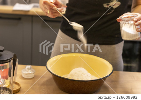 Woman adding ingredients together to prepare dough 126009992