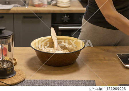 Woman adding ingredients together to prepare dough Woman adding ingredients together to prepare dough 126009998