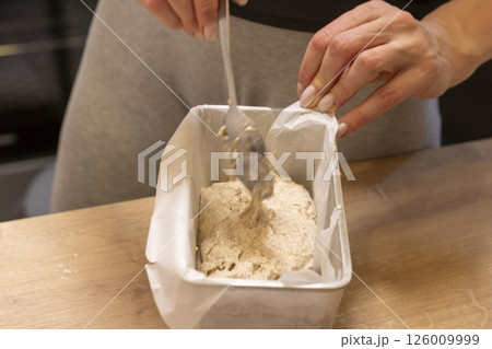 Woman adding ingredients together to prepare dough 126009999