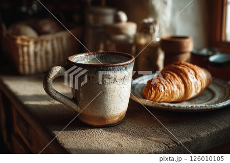 Rustic breakfast with ceramic mug and croissant in cozy kitchen 126010105