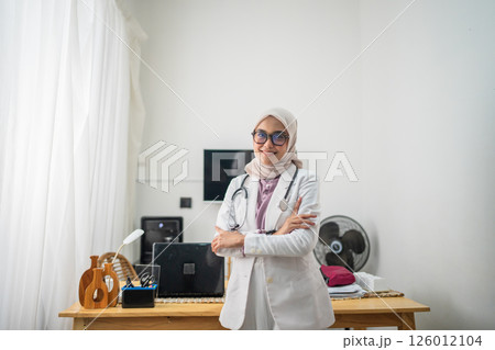 A confident female doctor stands proudly in a bright and welcoming clinic setting A confident female doctor stands proudly in a bright and welcoming clinic setting 126012104