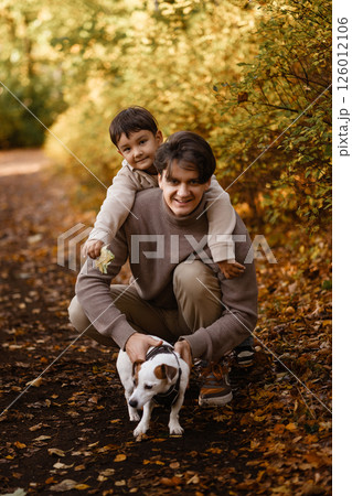 Smiling father and son in autumn park walking with dog Smiling father and son in autumn park walking with dog 126012106