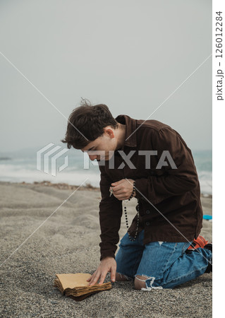 Man Praying With Passion On The Beach With The Bible Book 126012284